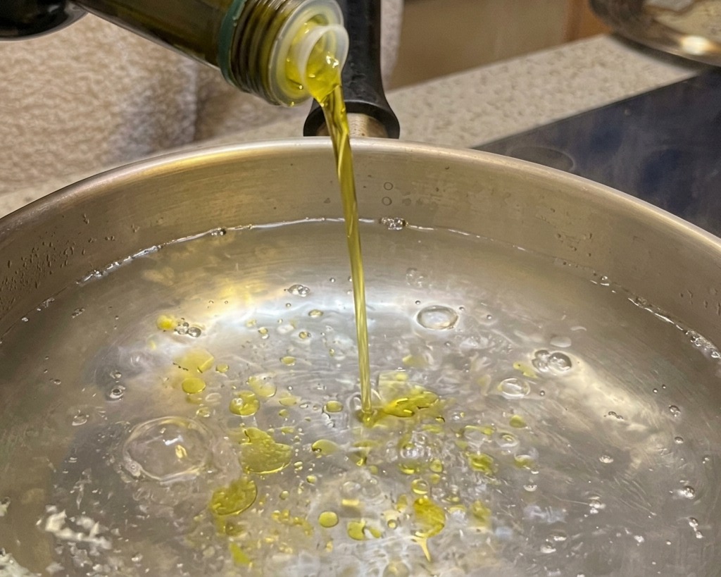 沸騰したお湯が入った鍋にオリーブオイルを入れている様子。