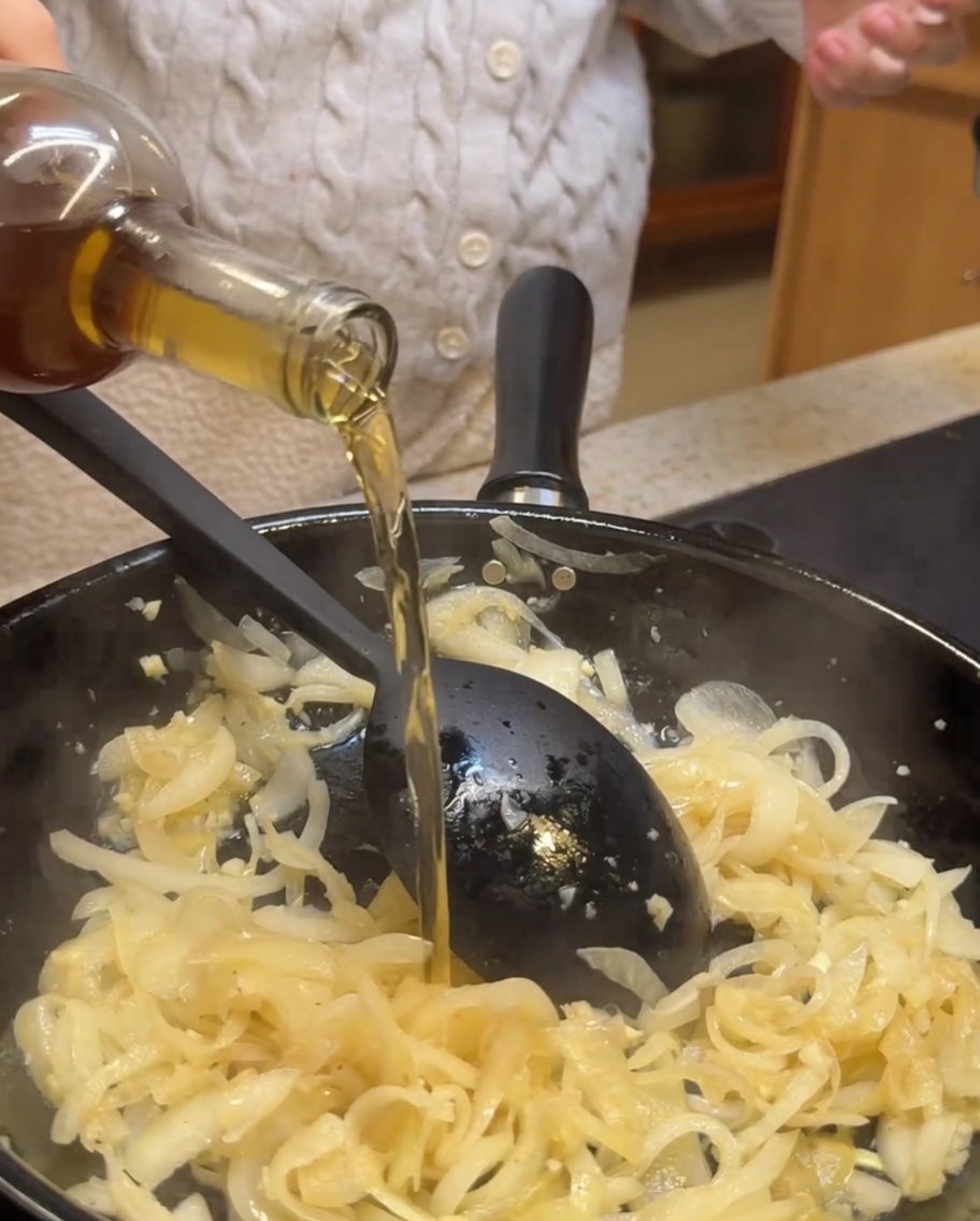 玉ねぎとにんにくが入ったフライパンに、白ワインとバルサミコ酢を注いでいる様子。