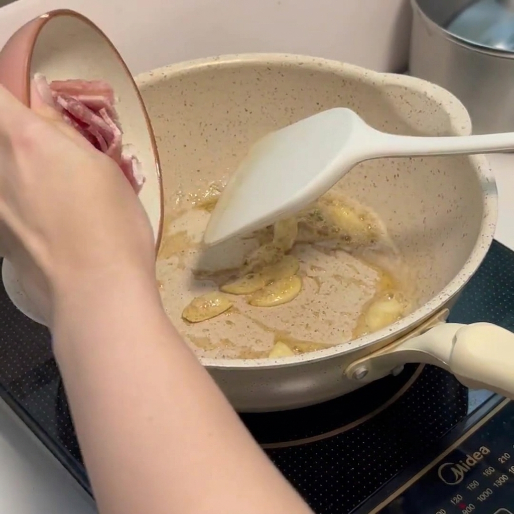 にんにくと一緒にベーコンを炒めている様子