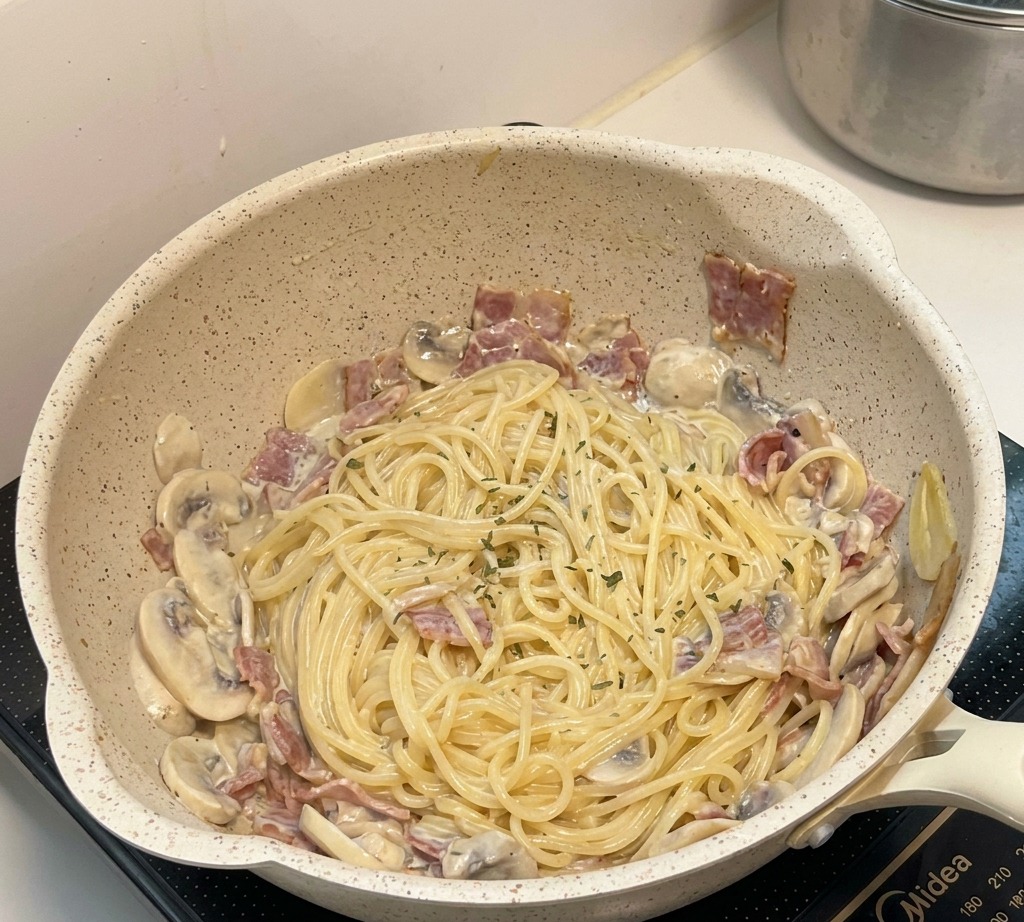 完成したパスタを盛り付け、パセリを振りかけている様子