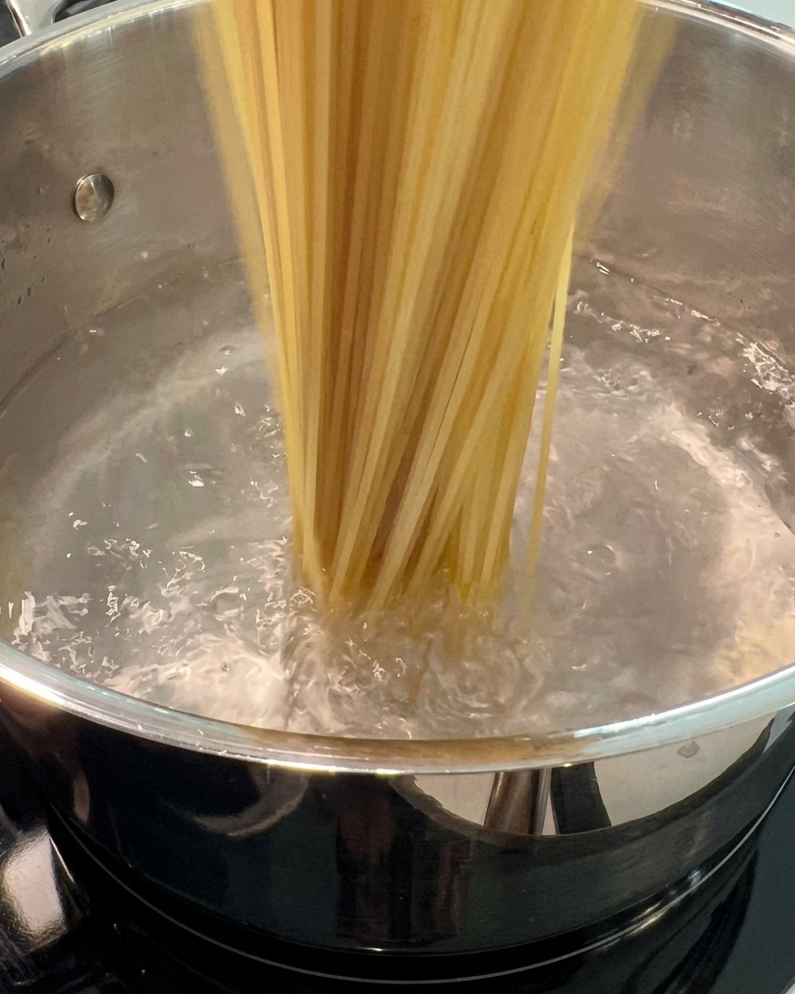 沸騰した大きな鍋にスパゲッティを入れている様子。