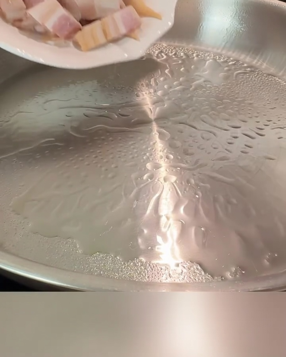 フライパンでベーコンが黄金色に焼けている様子。