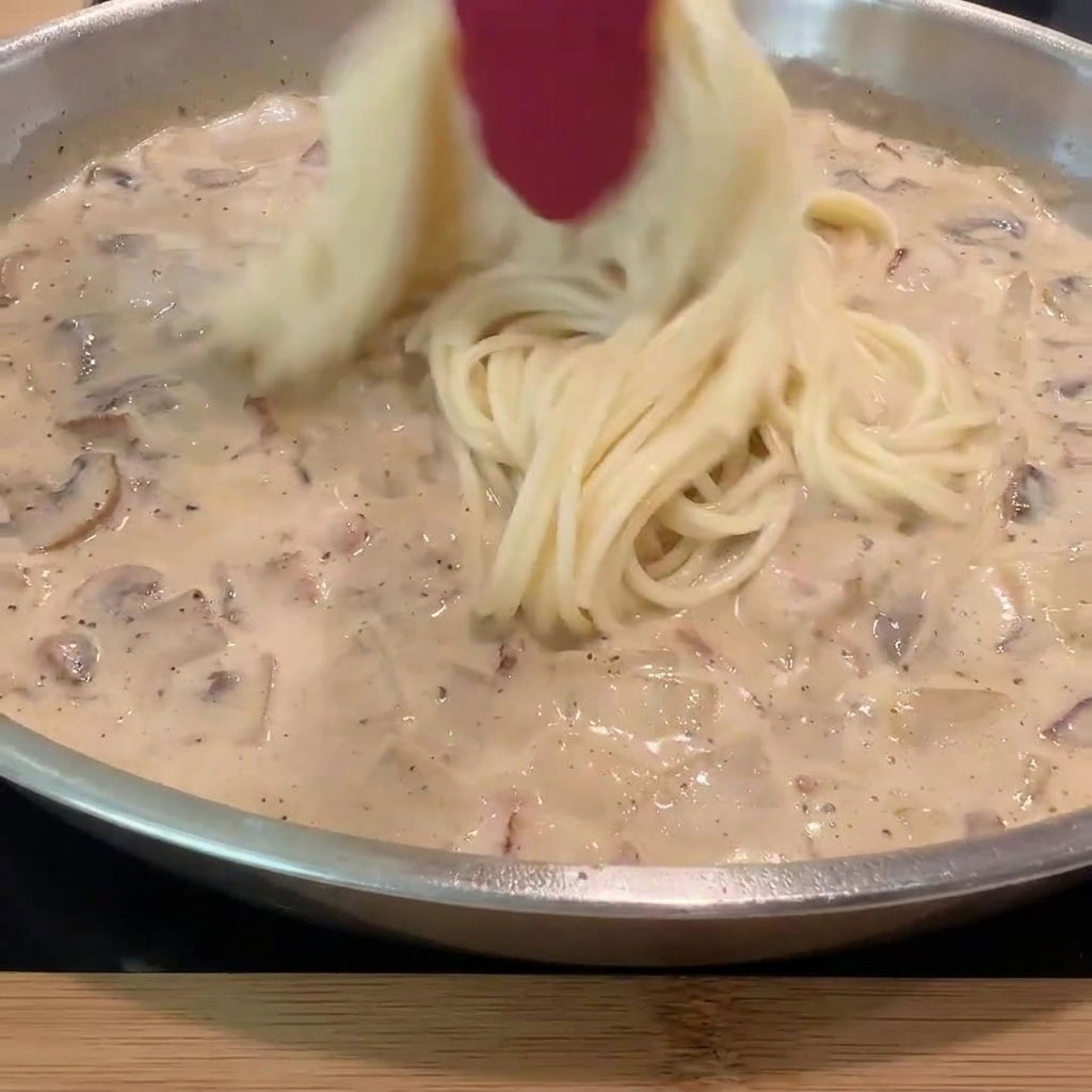 茹で上がったスパゲッティをソースの中に入れている様子。
