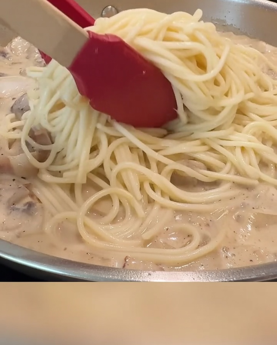 トングを使ってスパゲッティとソースを和えている様子。