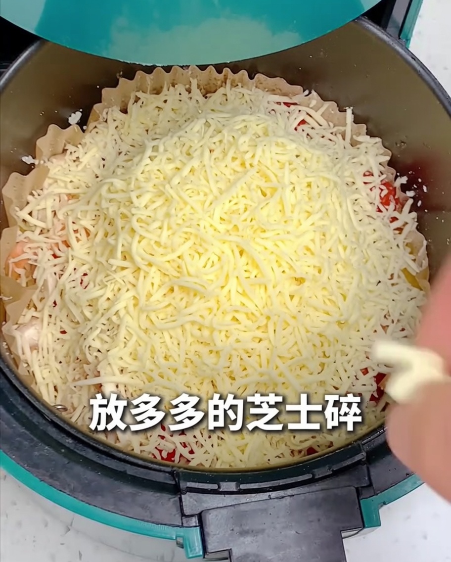 ピザ全体にたっぷりのシュレッドチーズを散らしている様子。