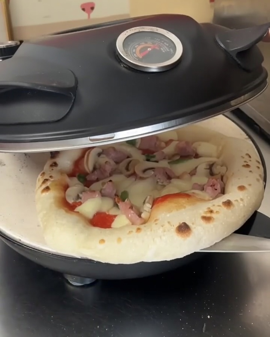 半分焼けてチーズが溶け始めたピザを、ピザピールを使ってオーブン内で回転させている様子。