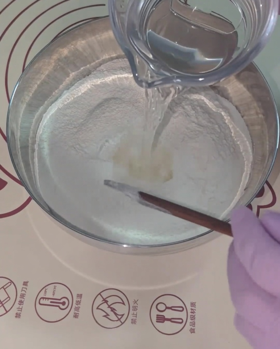 小麦粉のミックスにぬるま湯を注ぎ、菜箸で混ぜている様子。
