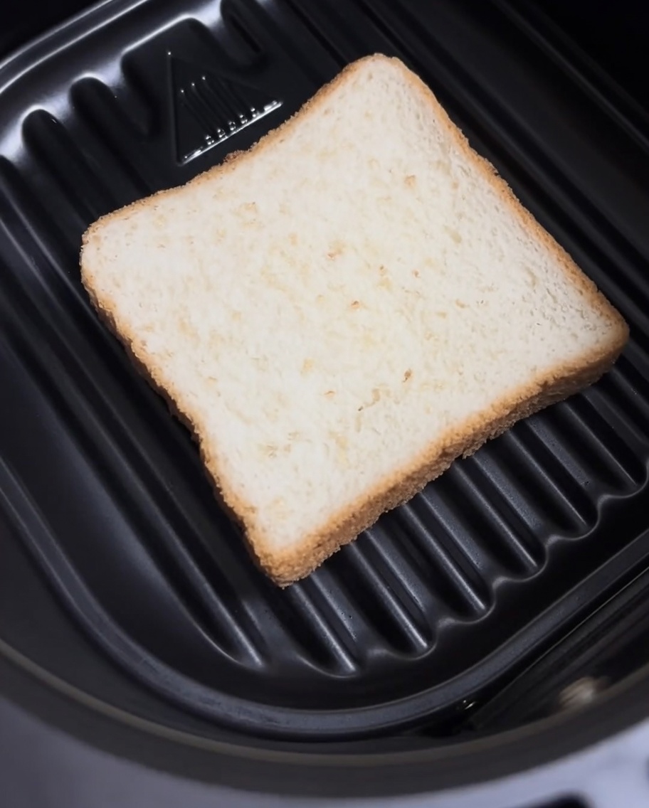 エアフライヤーのバスケットに食パンを1枚平らに置いている様子。