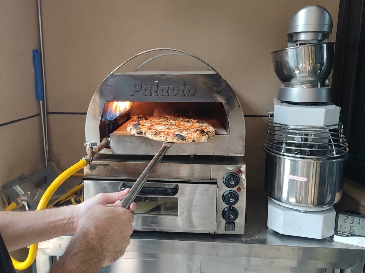焼き目がついた焼きたてのピザを、ピザピールでオーブンから取り出している様子。