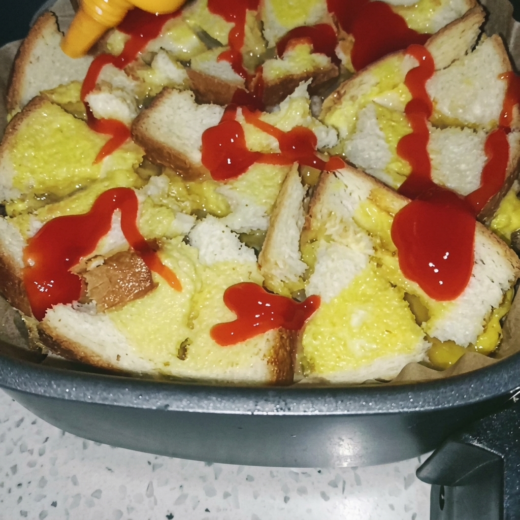 焼いたパンと卵の土台に、ハケで赤いトマトソースを塗っている様子。