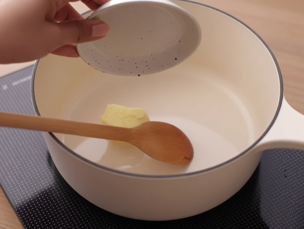 コンロに置かれた白い小鍋の中で溶けていくバター。