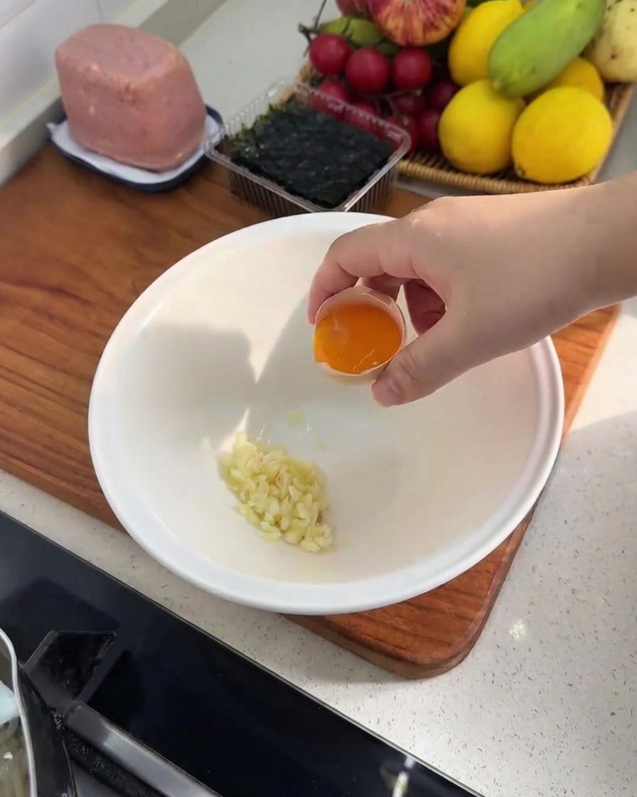 みじん切りにしたにんにくと、鮮やかな卵黄が白いボウルに入っている様子。