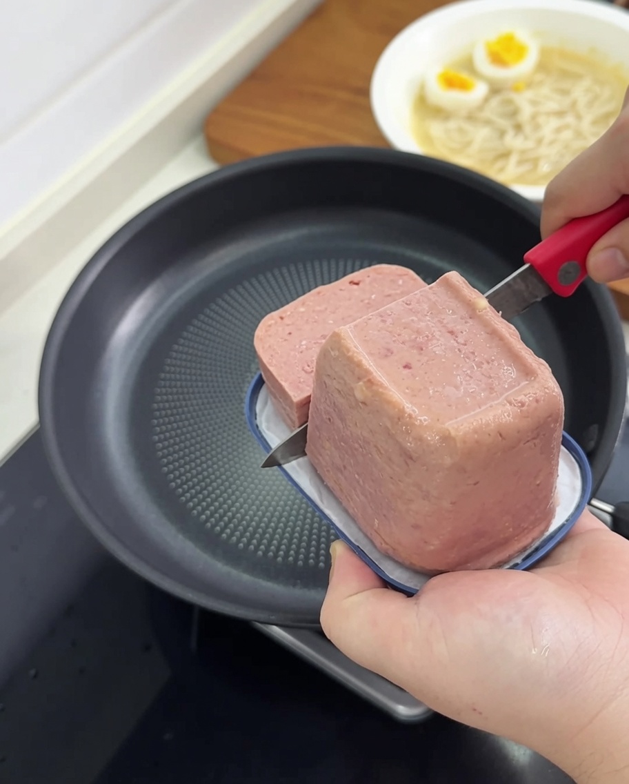 フッ素樹脂加工のフライパンで、ランチョンミートの表面がきつね色になるまで焼いている様子。
