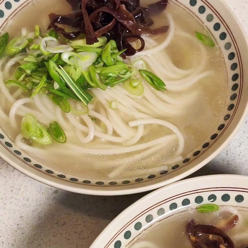 麺の上に炒めた具材、チャーシュー、卵を乗せている様子。