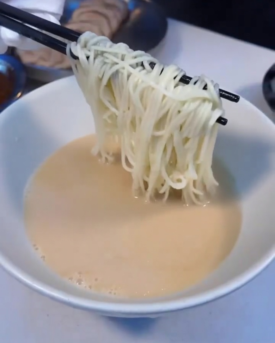 茹で上がった麺をスープの入った丼に移している様子
