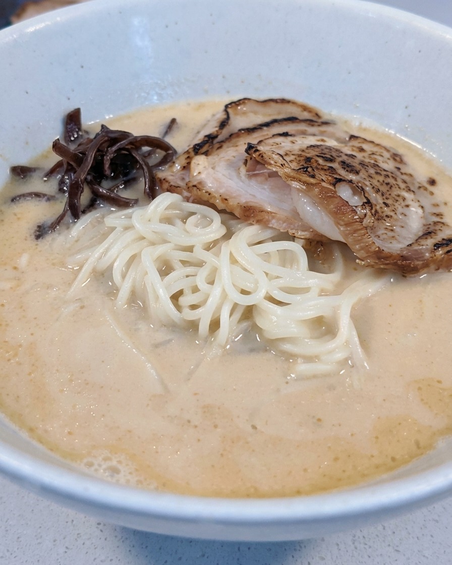 きくらげとメンマを丼に盛り付けている様子