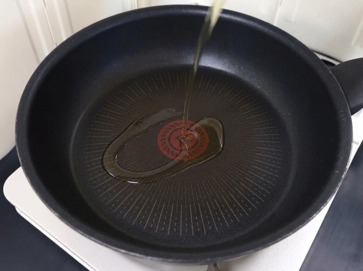 フライパンで豚薄切り肉を油で焼いている様子。