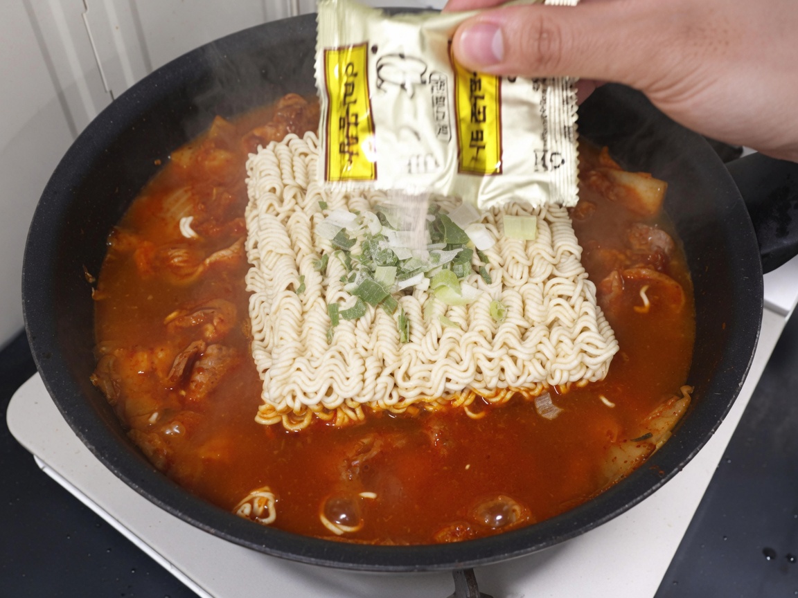 スープにラーメンの粉末スープとかやくを入れている様子。