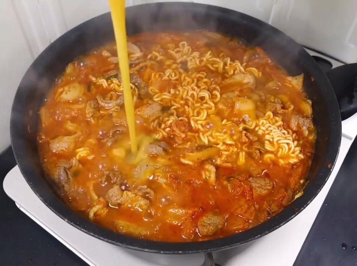 煮込み中の鍋に溶き卵を回し入れている様子。