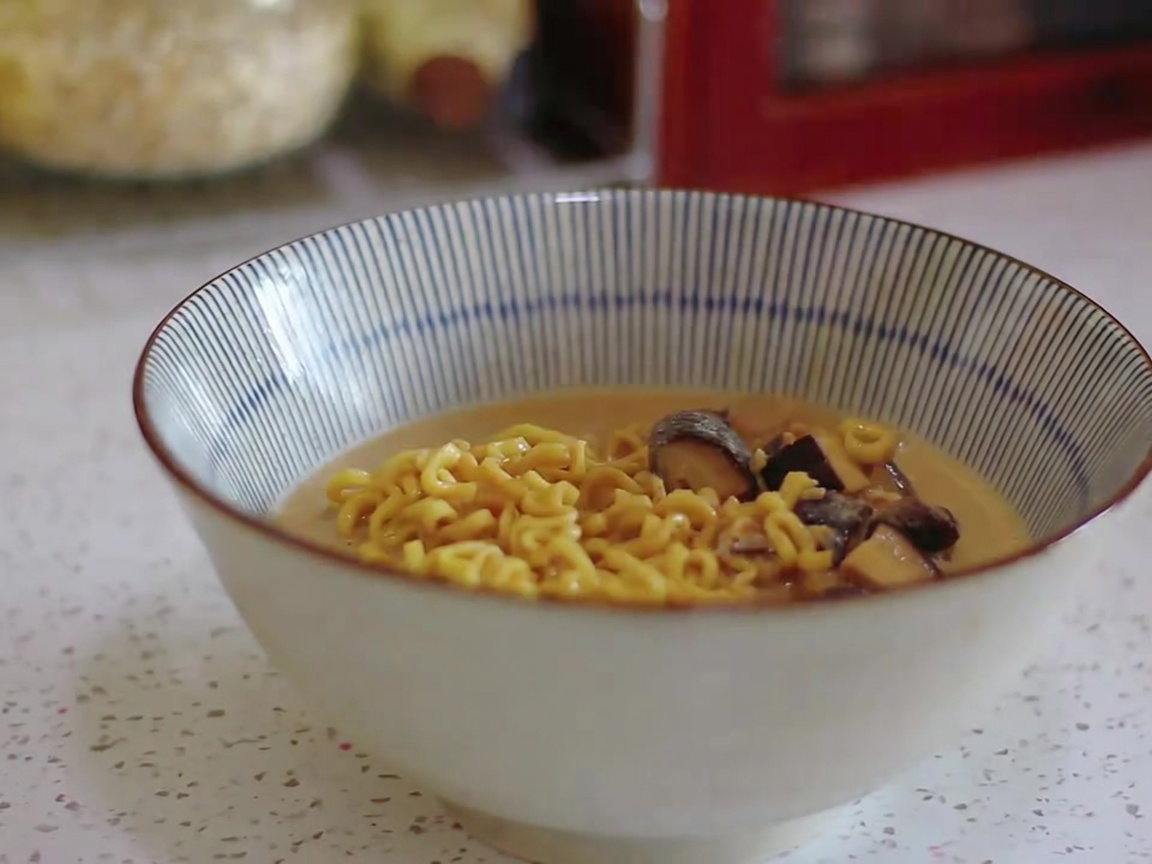 クリーミーなスープと麺を縞模様の丼に移している様子。