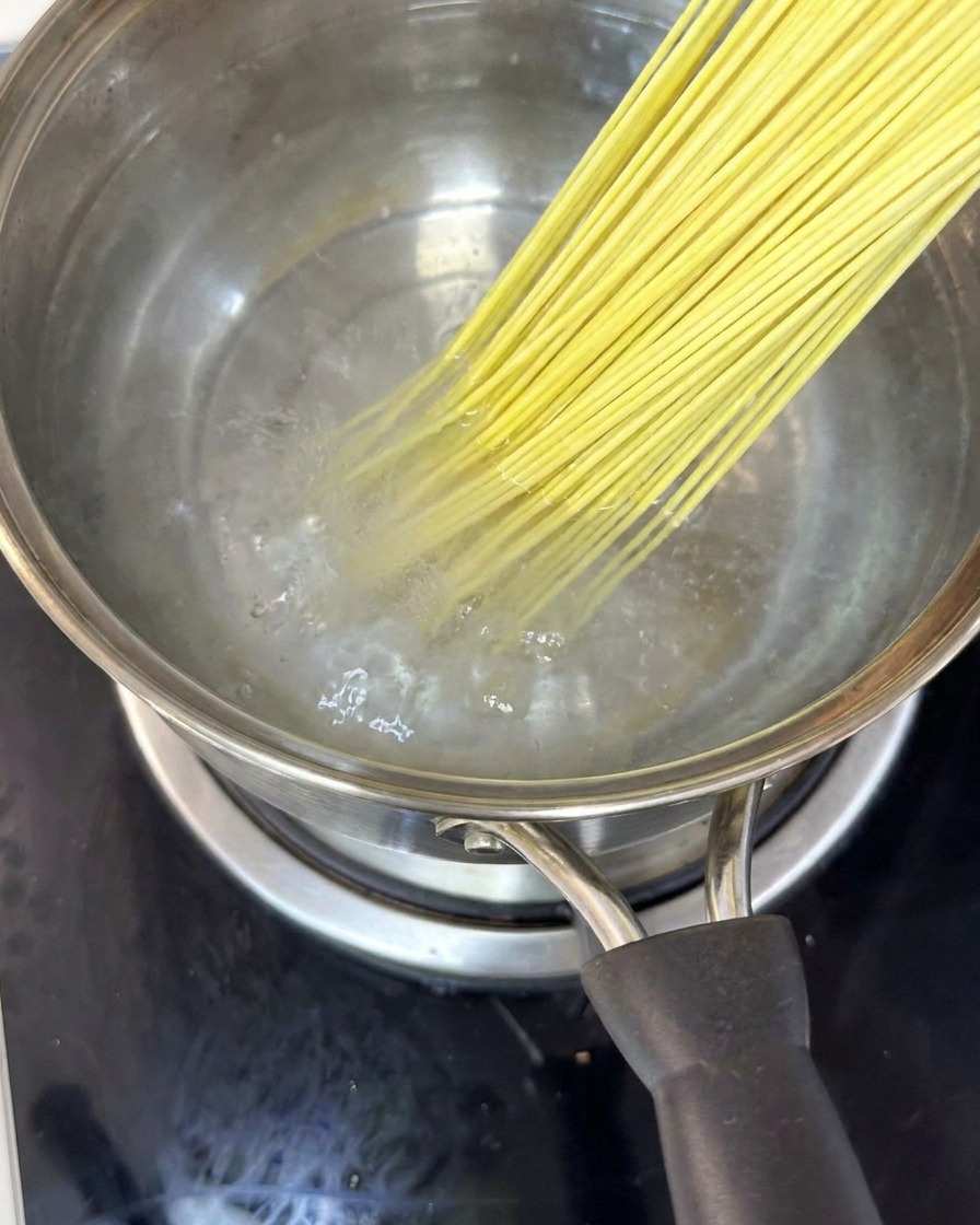 沸騰した鍋で茹でられている麺を菜箸でほぐしている様子。