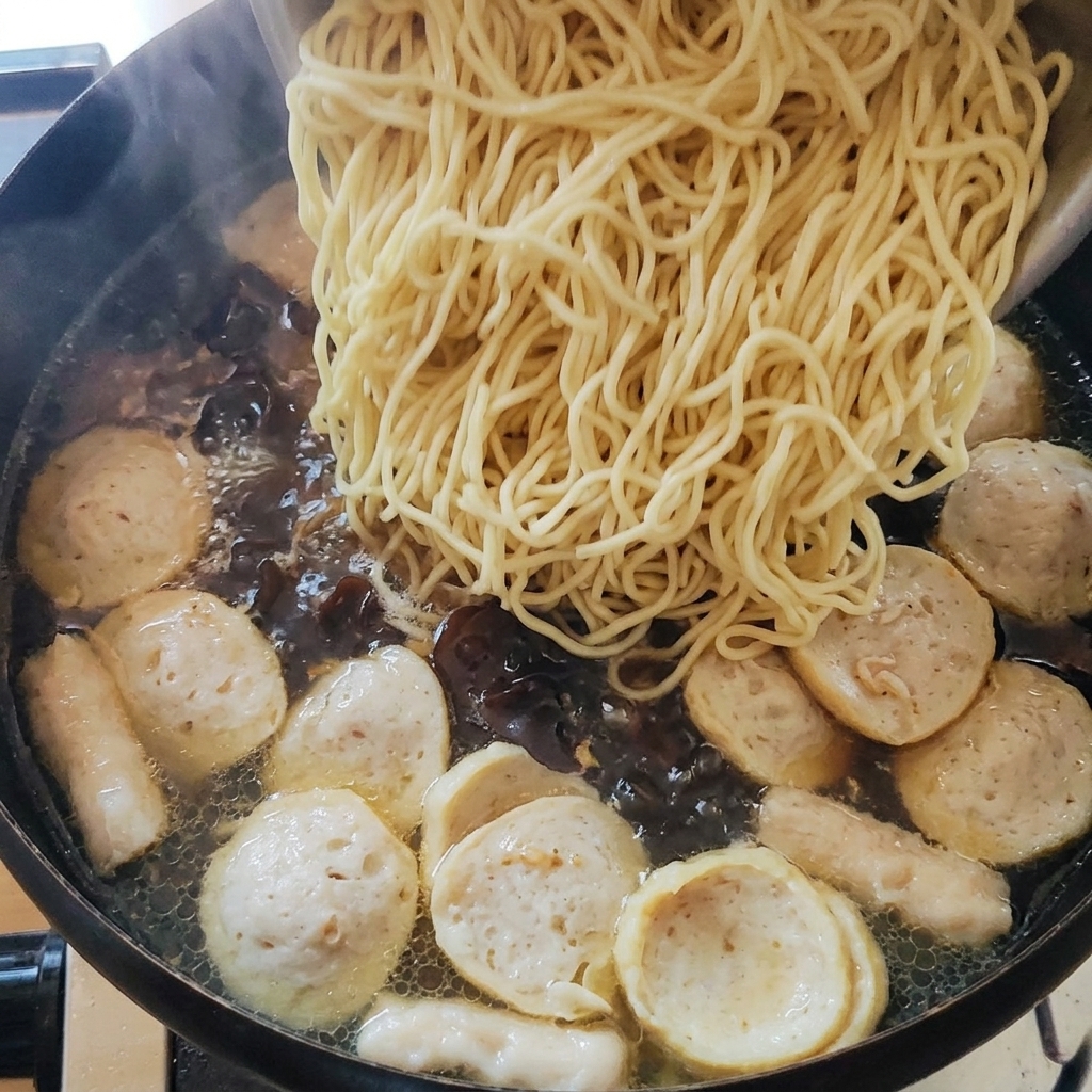 茹でた麺をスープの入った鍋に加えている様子