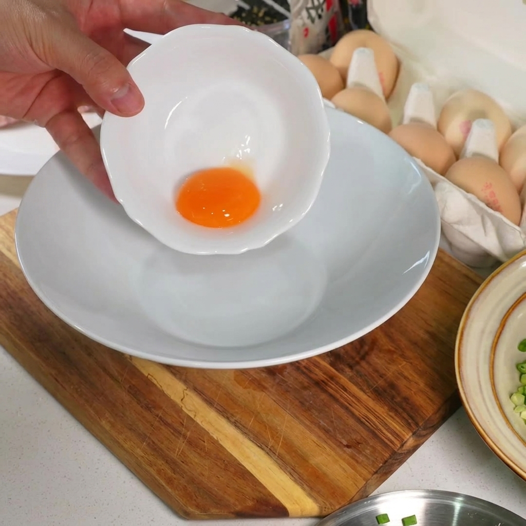 真っ白な陶器のボウルの底に置かれた、鮮やかな生の卵黄。