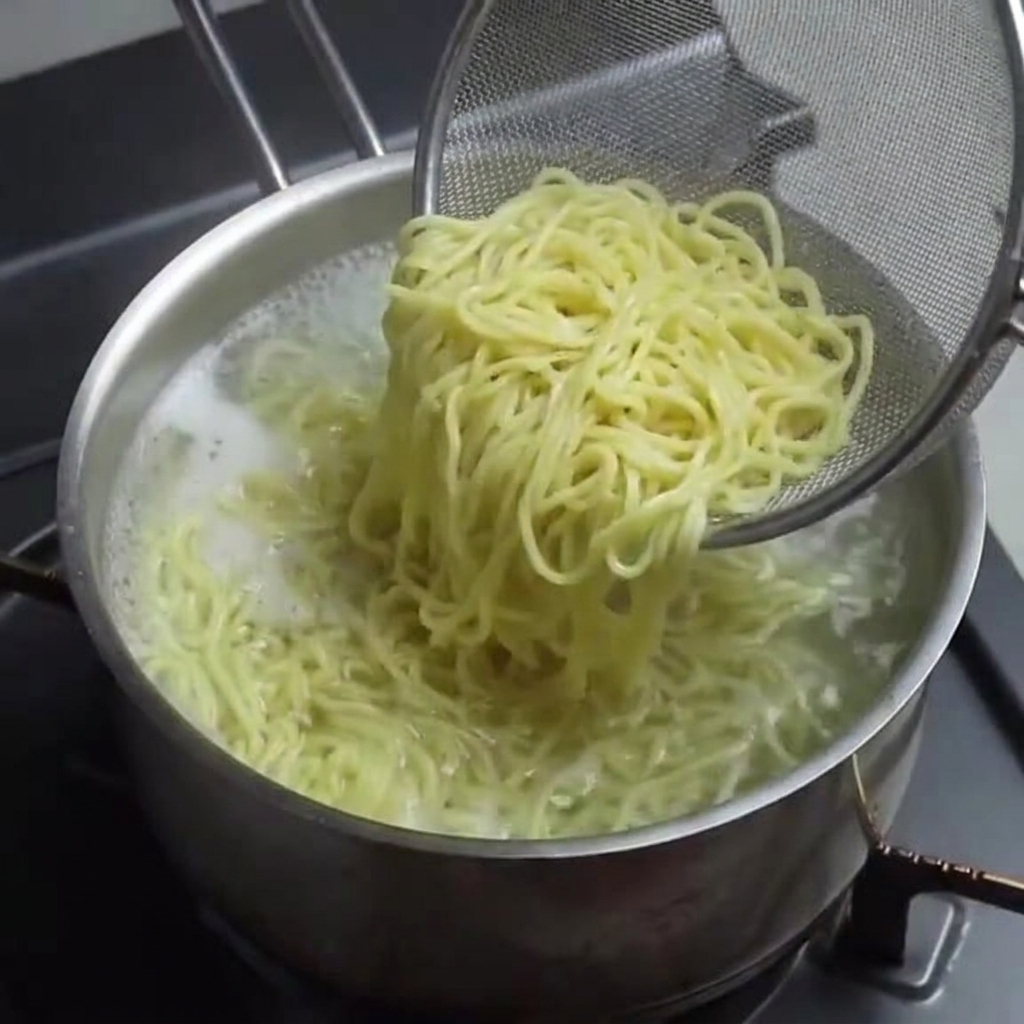 ザルを使ってゆで上がった麺の湯切りをしている様子。