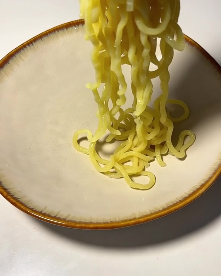 茹で上がった麺をザルにあげる様子