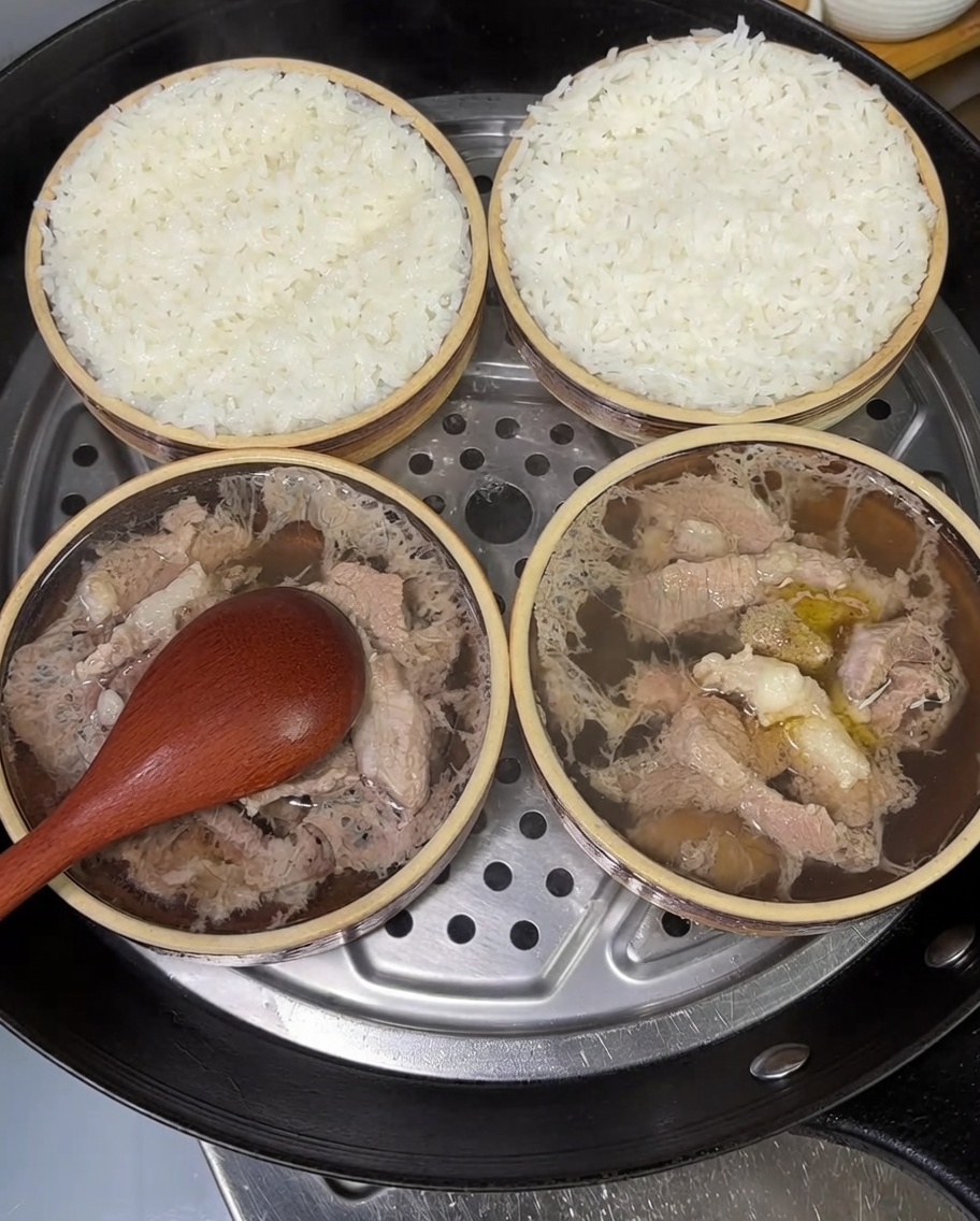 刻んだ青ねぎがたっぷりと乗せられた、2つの蒸し豚肉ごはんの器。