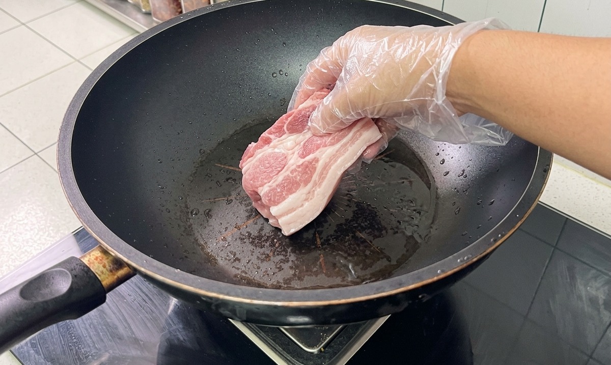 中華鍋で豚骨と豚バラ肉を香味野菜と一緒に下茹でしている様子。