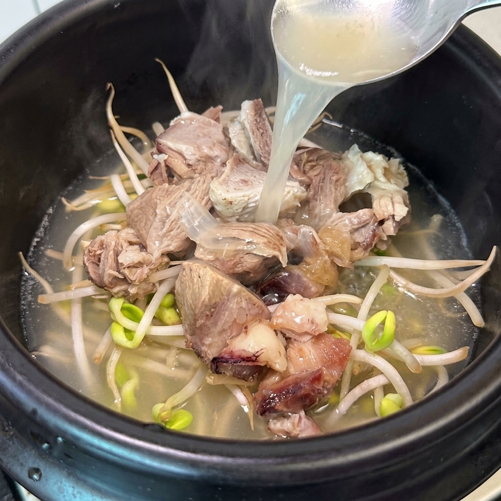 具材の入った土鍋に熱いスープを注ぎ入れている様子。