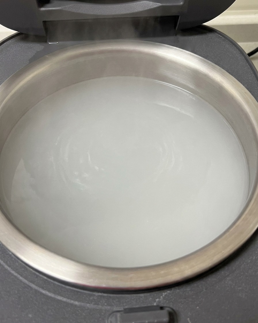 炊飯器の中で熱湯に浸かる豚スペアリブのクローズアップ。
