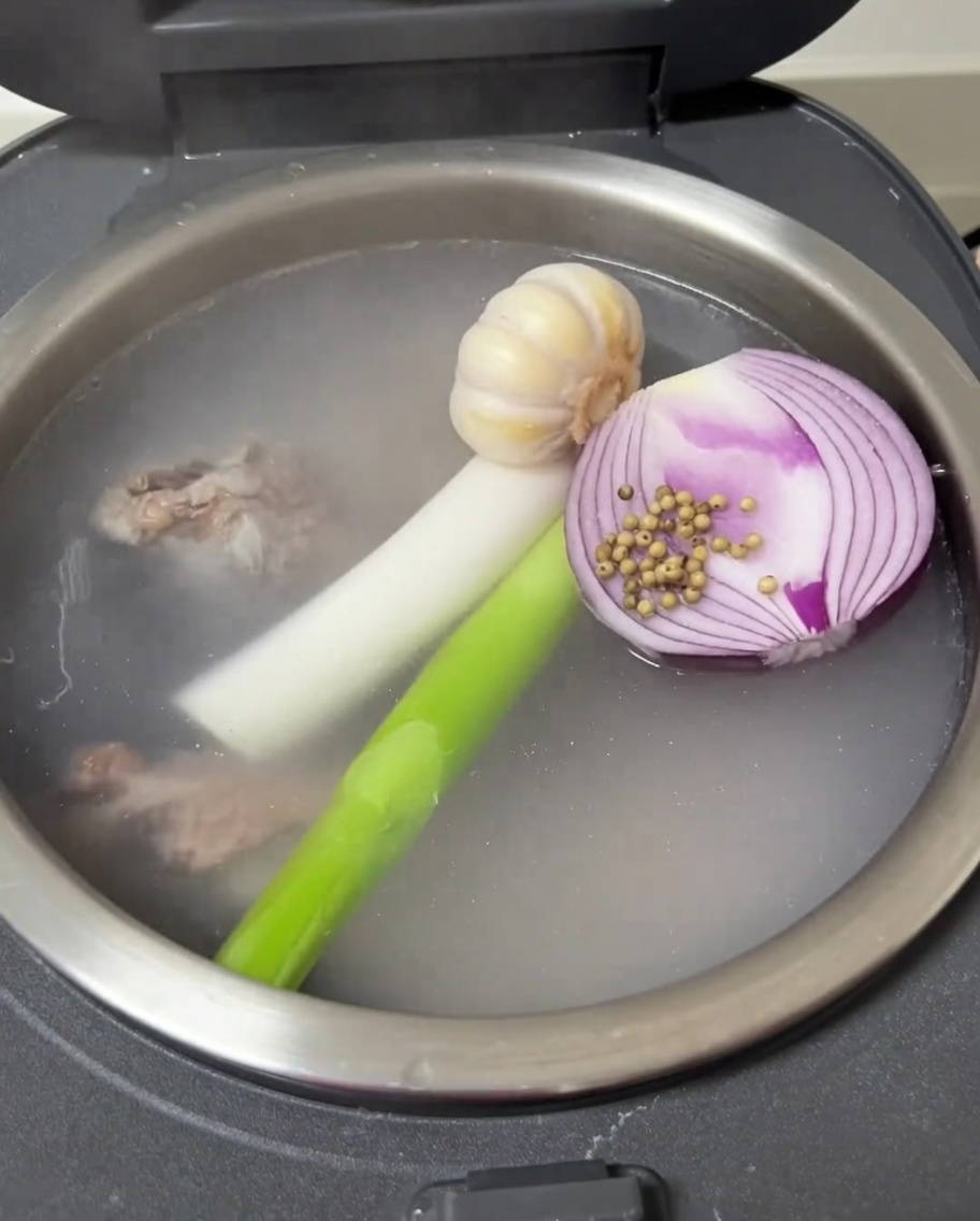 炊飯器の中にニンニク、玉ねぎ、ネギが入っている様子。