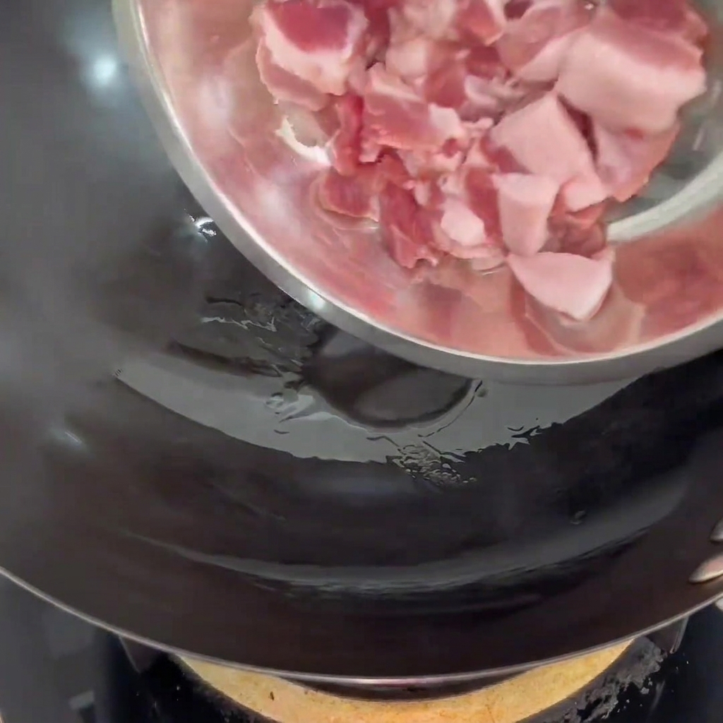 熱したフライパンで豚バラ肉を焼く様子。