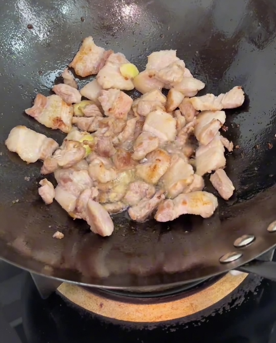 豚バラ肉に醤油を回し入れる様子。