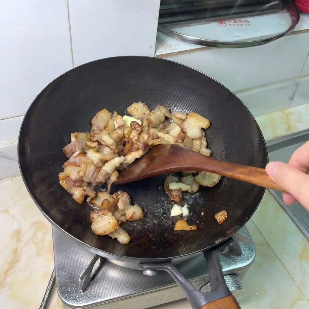つぶしたニンニクと豚肉を炒めている様子