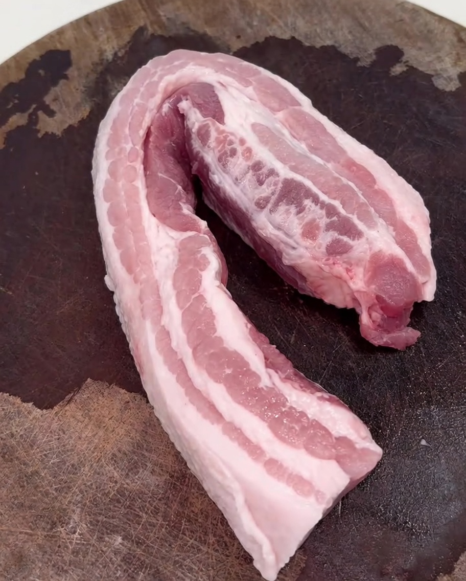 熱した中華鍋で豚バラ肉を炒めている様子。