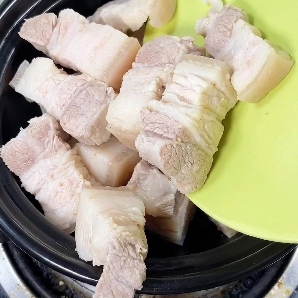 下茹でされた豚肉が土鍋の中に丁寧に入れられている様子。