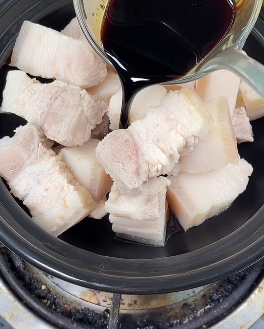 土鍋の中の豚肉に醤油と氷砂糖を加えている様子。