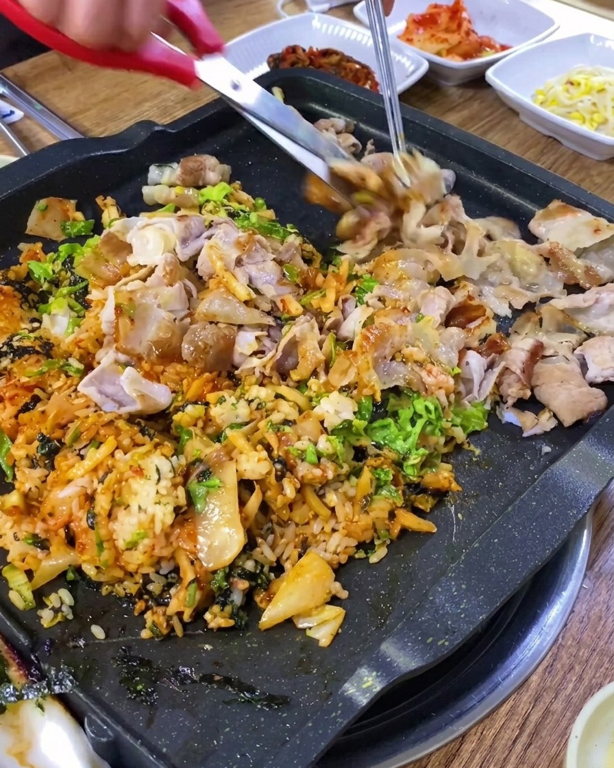 キッチンバサミで鉄板上の豚肉を細かく切る様子。