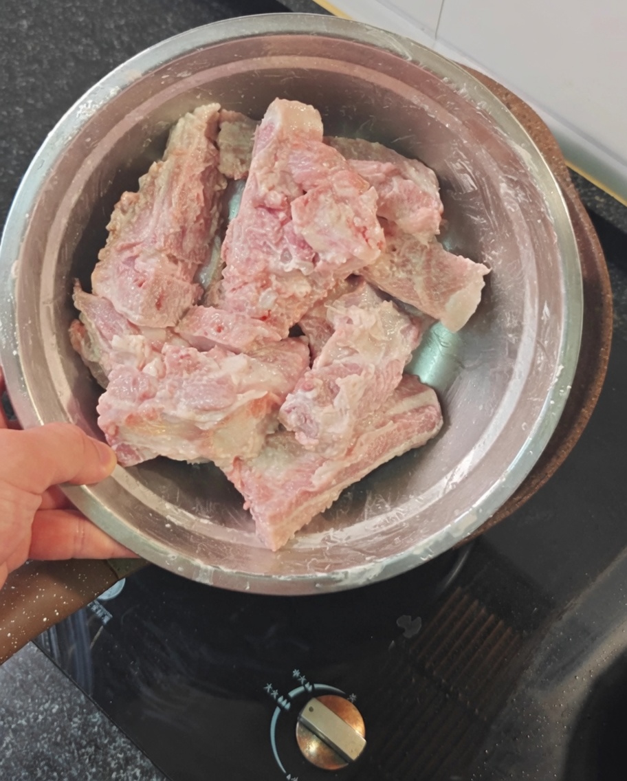 ボウルに入った赤片栗粉をまぶした生の豚スペアリブ。