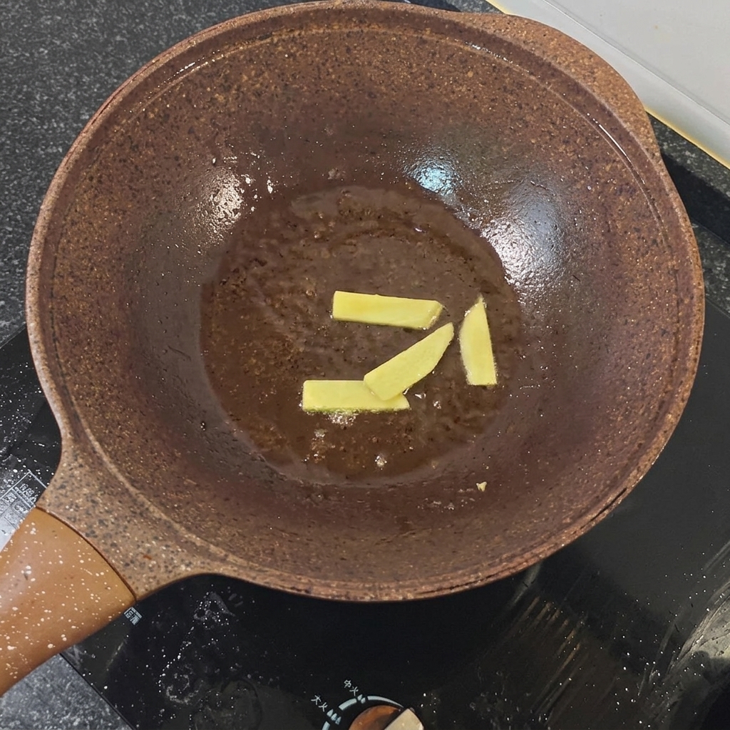 フライパンで炒められている生姜スライスと赤玉ねぎ。