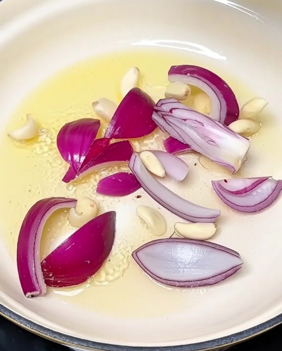 鍋でスライスした玉ねぎとにんにくを炒めている様子。