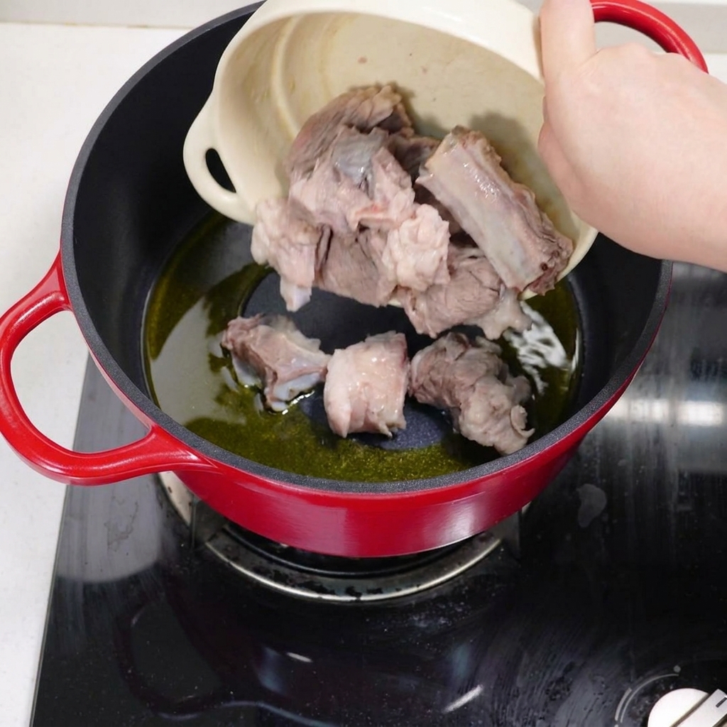 下茹でしたスペアリブを鍋で油を熱して焼き色をつけている様子