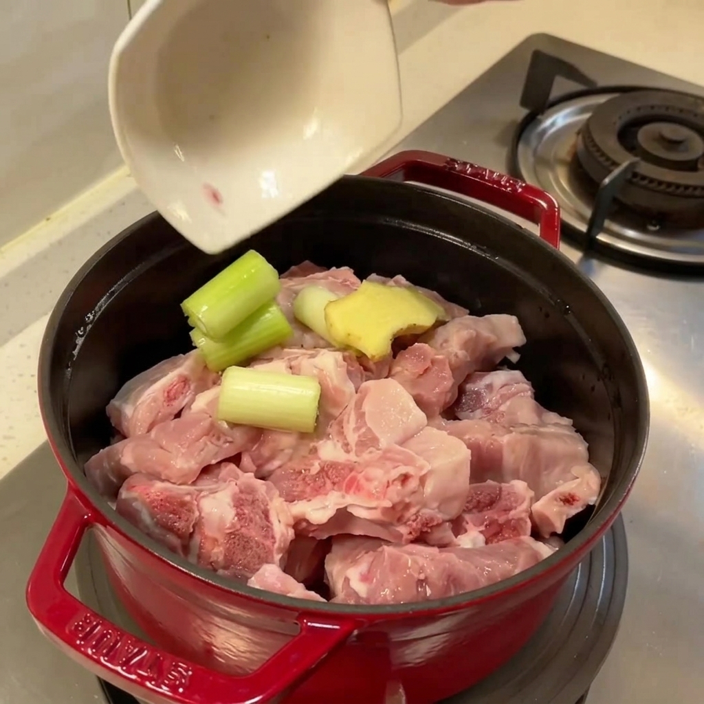 生の豚スペアリブ、生姜、青ネギが入った、茹でる直前の鍋。
