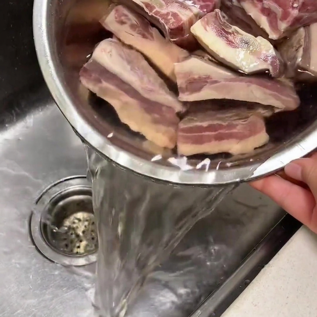 キッチンのシンクで、ボウルに入った冷水に浸されている牛カルビ肉。