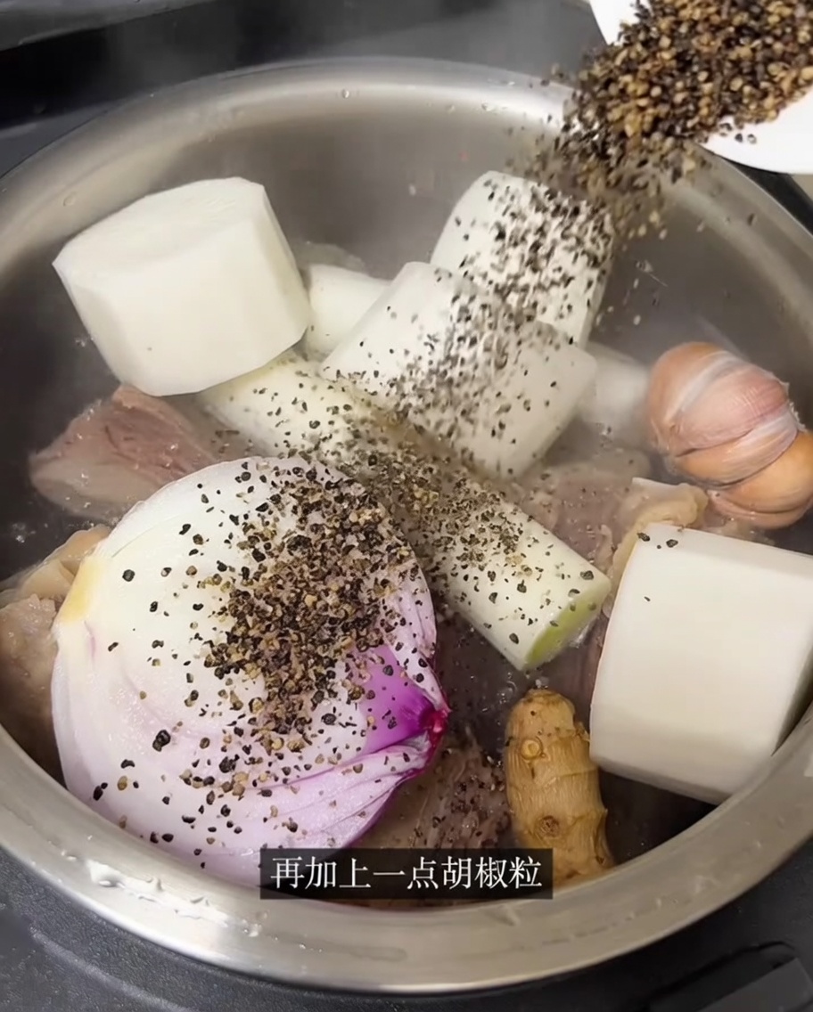 炊飯器の中の牛肉と香味野菜の上から熱湯が注がれている様子。