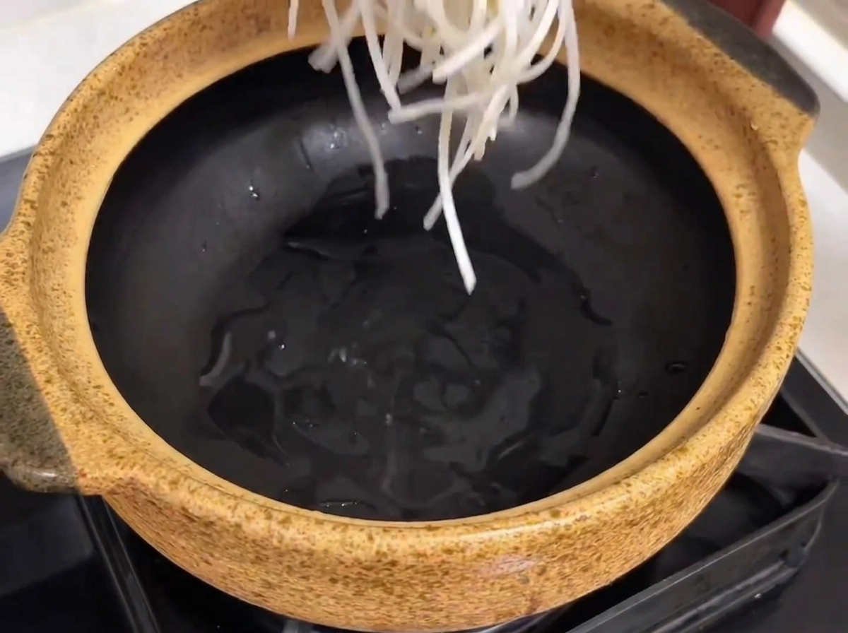 春雨、柔らかい牛カルビ肉、大根の塊が中に入れられている陶製の盛り付け用ポット。