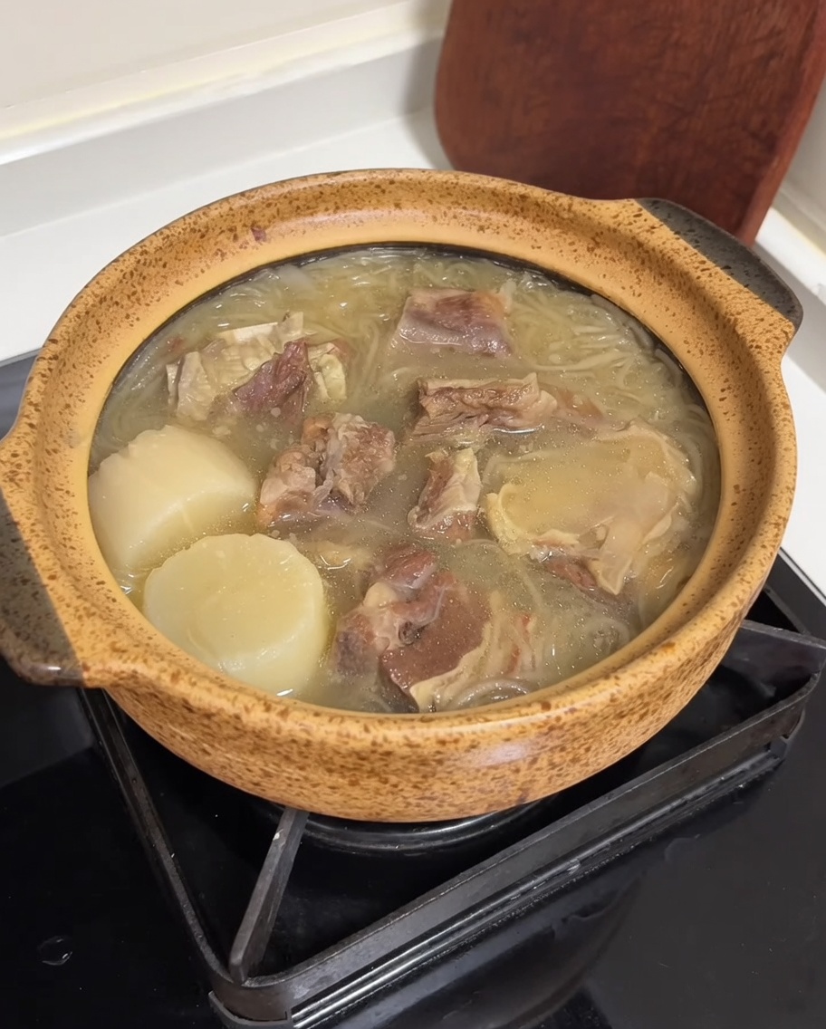 牛スープが入った陶製のポットに、鮮やかな黄色の卵の細切りと鮮やかな緑色のスライスネギがトッピングされている様子。